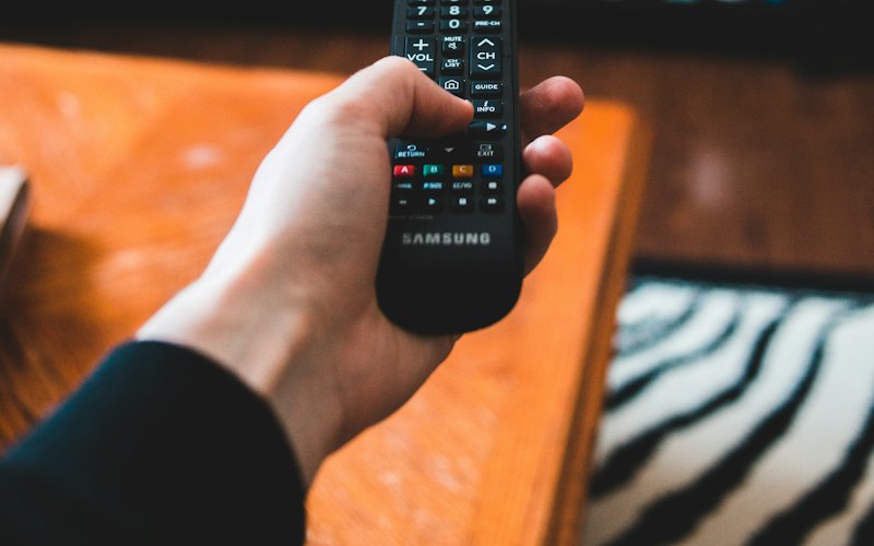 A hand pointing a remote at a TV screen full of streaming thumbnails