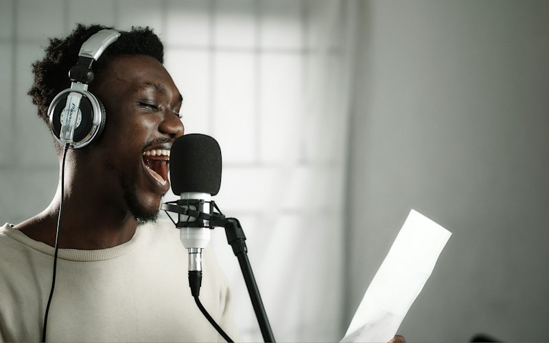 A man in headphones singing into a studio microphone