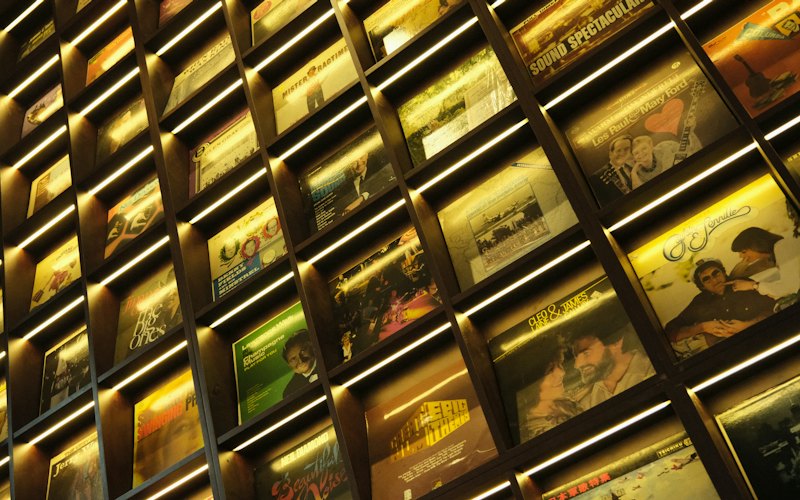 A wall of backlit vinyl record sleeves in a record shop